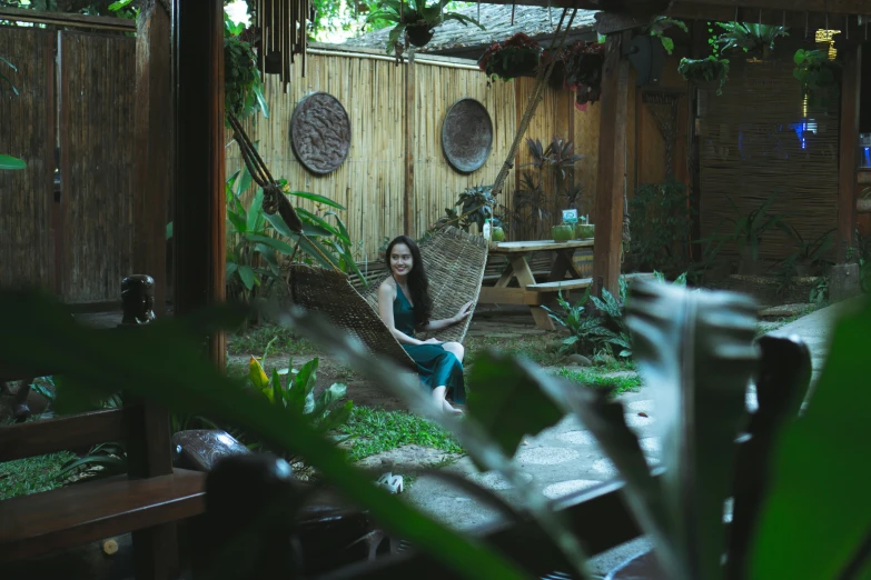 a woman sitting in an old fashioned hammock by a pool