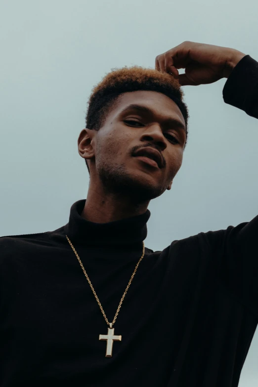 a young black male with an extremely small cross on his cross necklace