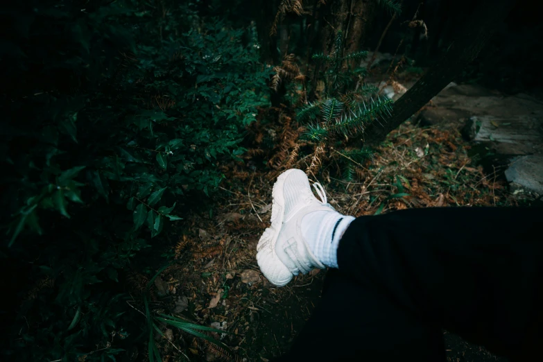 a person standing in the woods with white shoes on