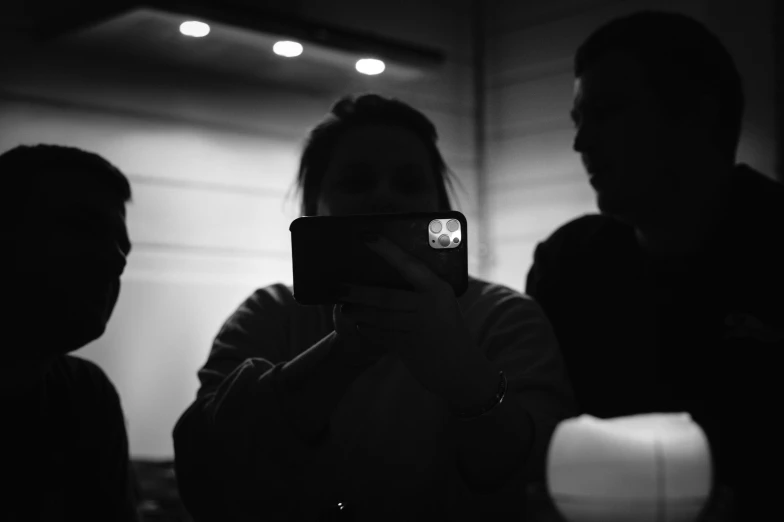 a black and white po of three people looking at their cell phone