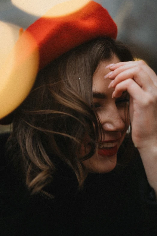 a young woman wearing a red hat is looking through her fingers