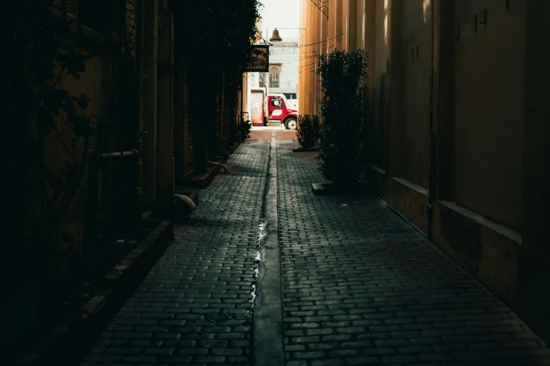 a narrow alley with a red car on the side