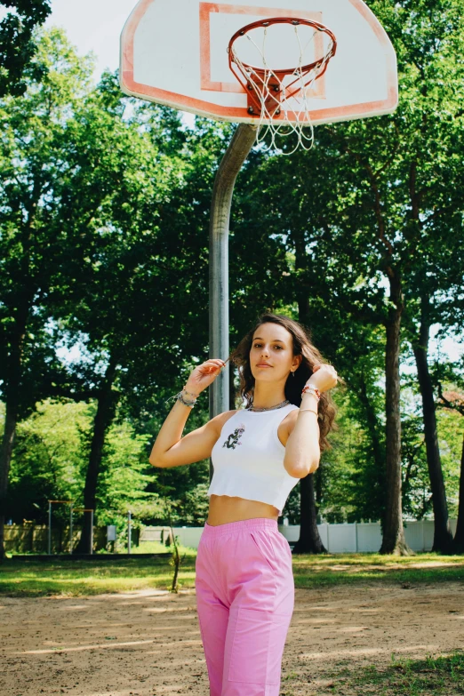 a young woman holding a basketball in front of a hoop