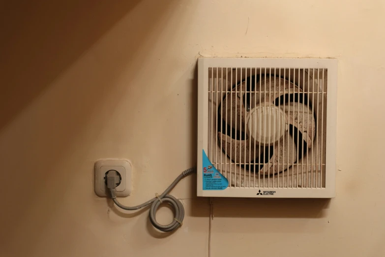 an exhaust fan on the wall with two wires running around