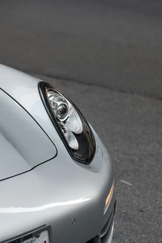 the front of a silver sports car driving on the road