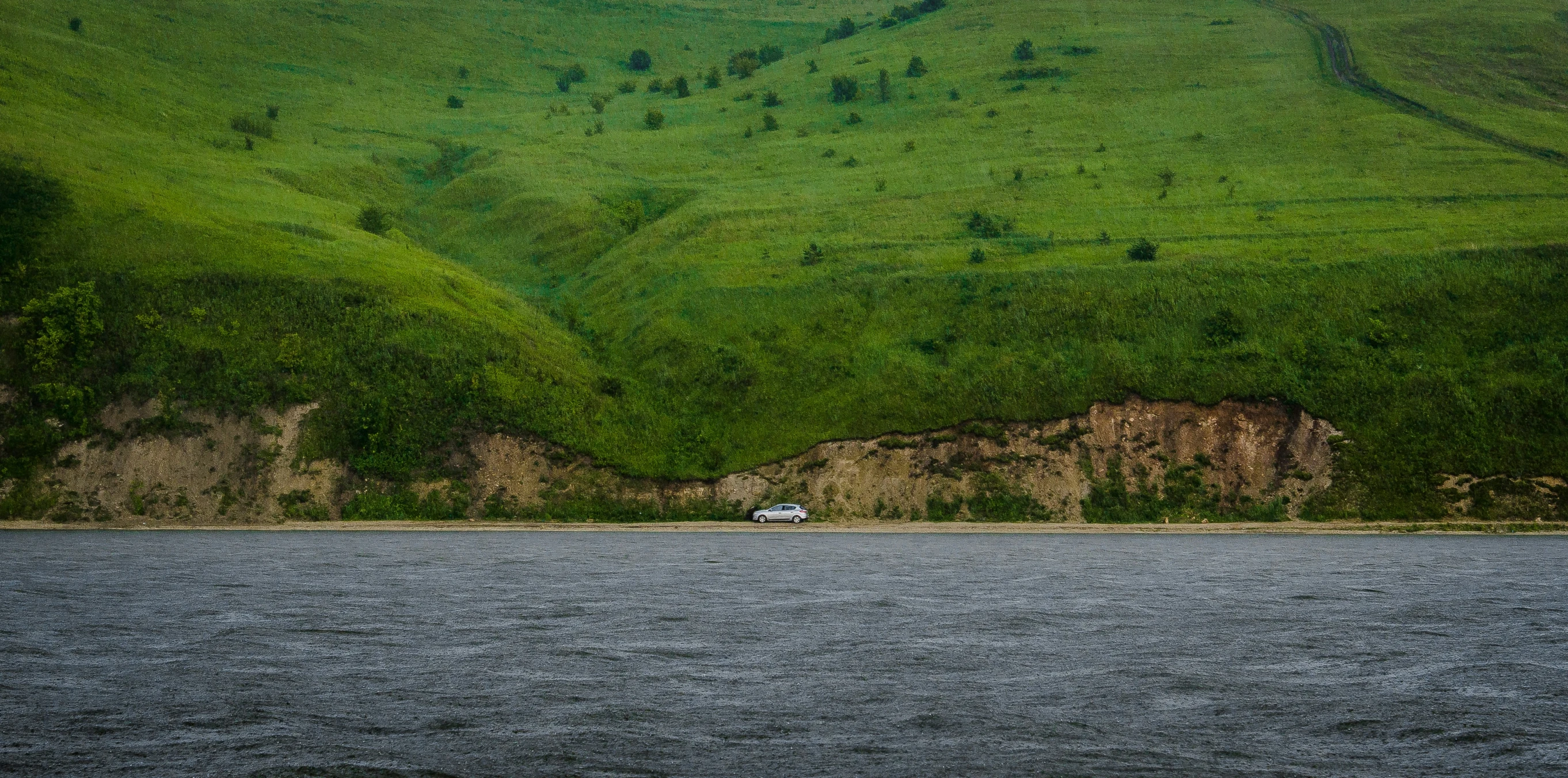 green mountains on either side of the water with a boat parked in front