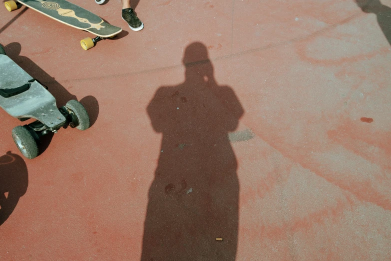 skateboarders are casting shadows on a red pavement