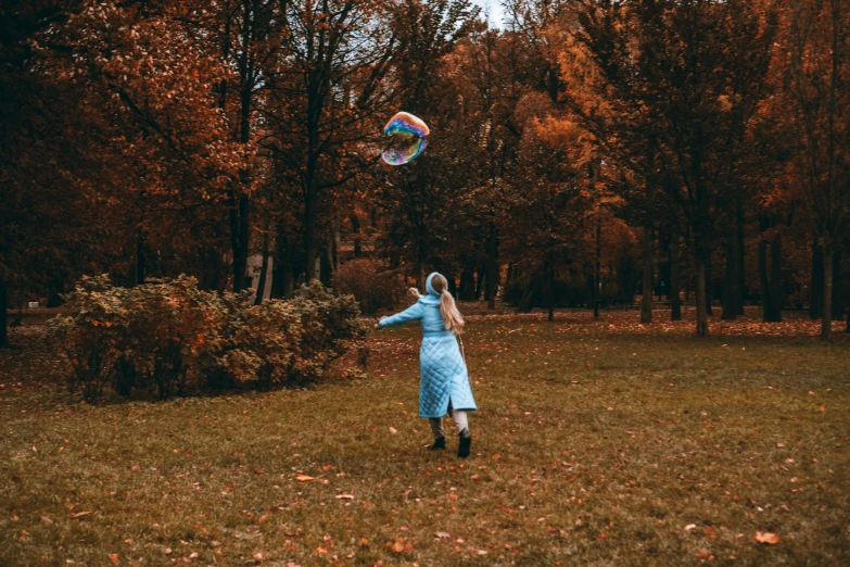 a woman wearing a blue dress flying a kite