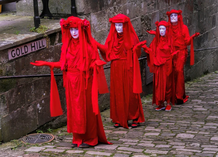 five people dressed in red are posed on a stone pathway