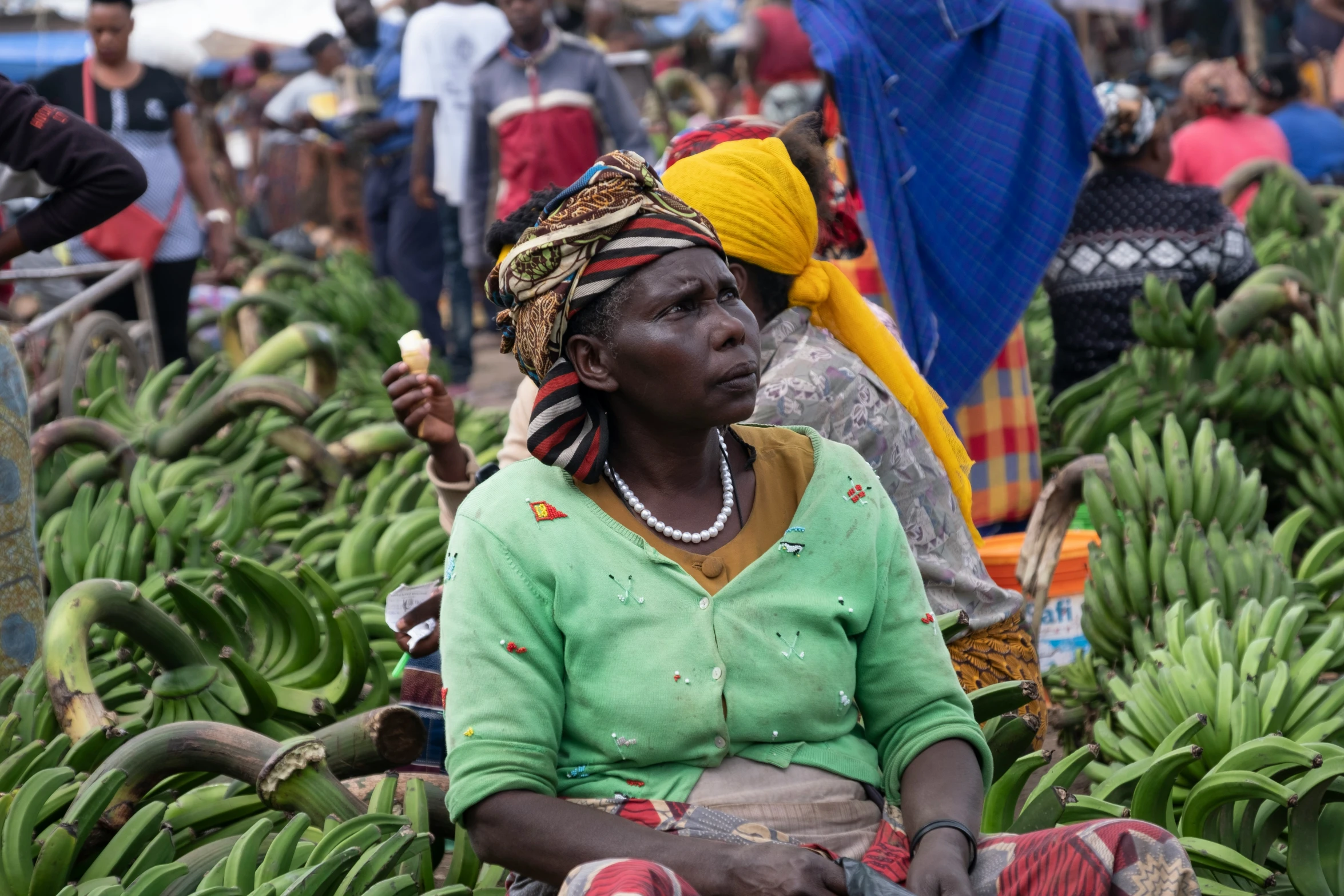 a woman sitting on top of a bunch of green bananas