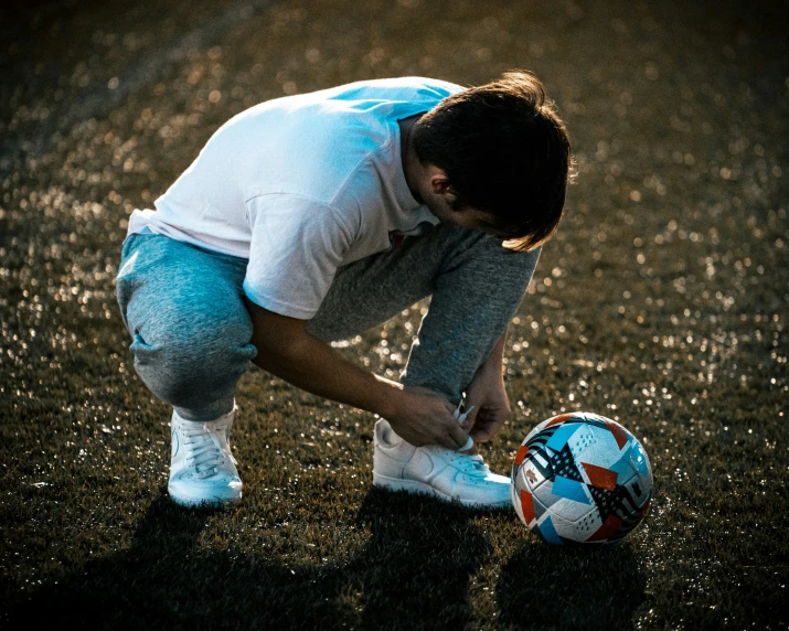 the boy is crouching with his foot on a soccer ball