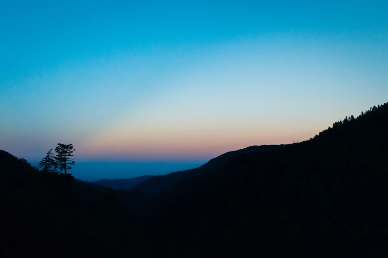 view of the sky from above a hill with forest