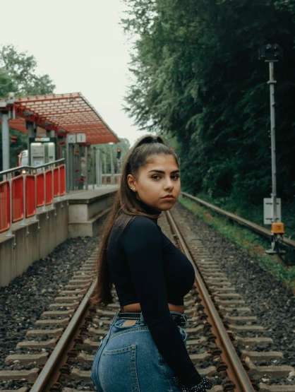a girl with long dark hair sitting on the railway tracks