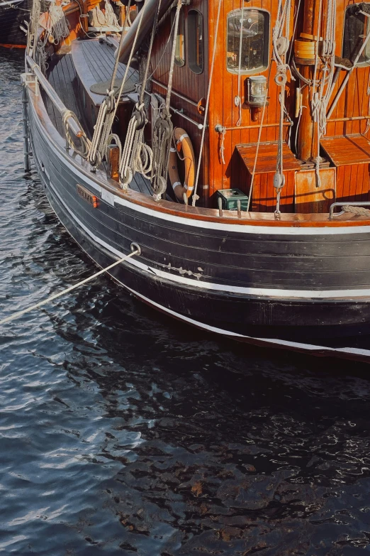 an orange and black boat floating on top of water