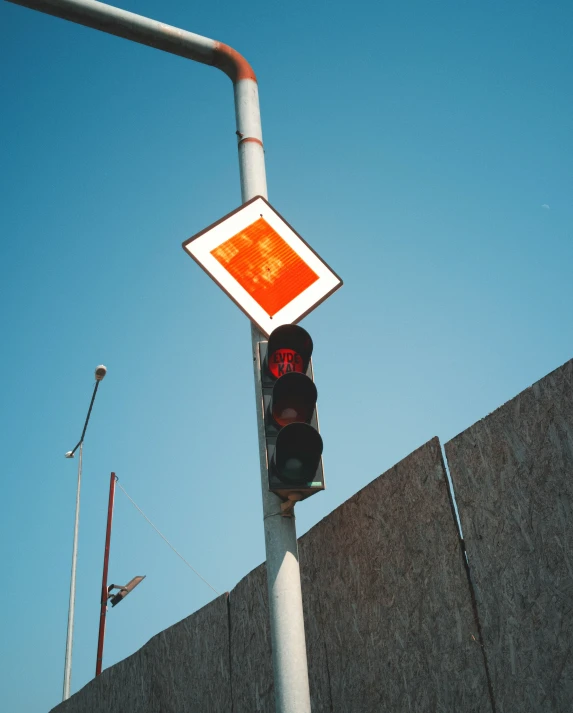 an orange traffic light and a white sign on top