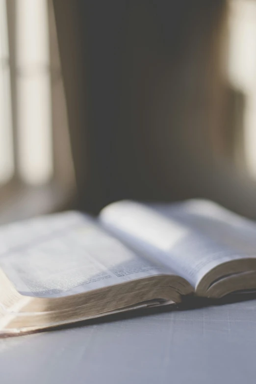 an open book is on a table with sunlight streaming in through the window