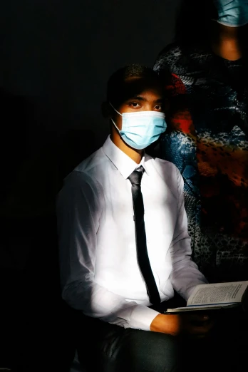 there is a man wearing a face mask and holding a book