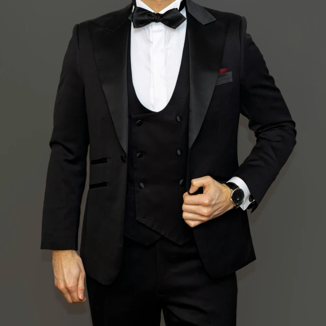 man in tuxedo standing in front of grey background