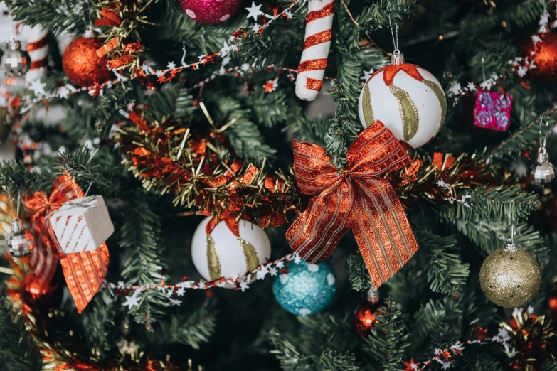 ornaments on a christmas tree with silver and red bows