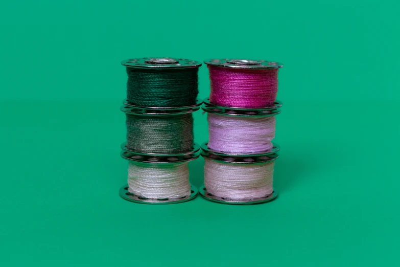 five spools of colored thread on a green background