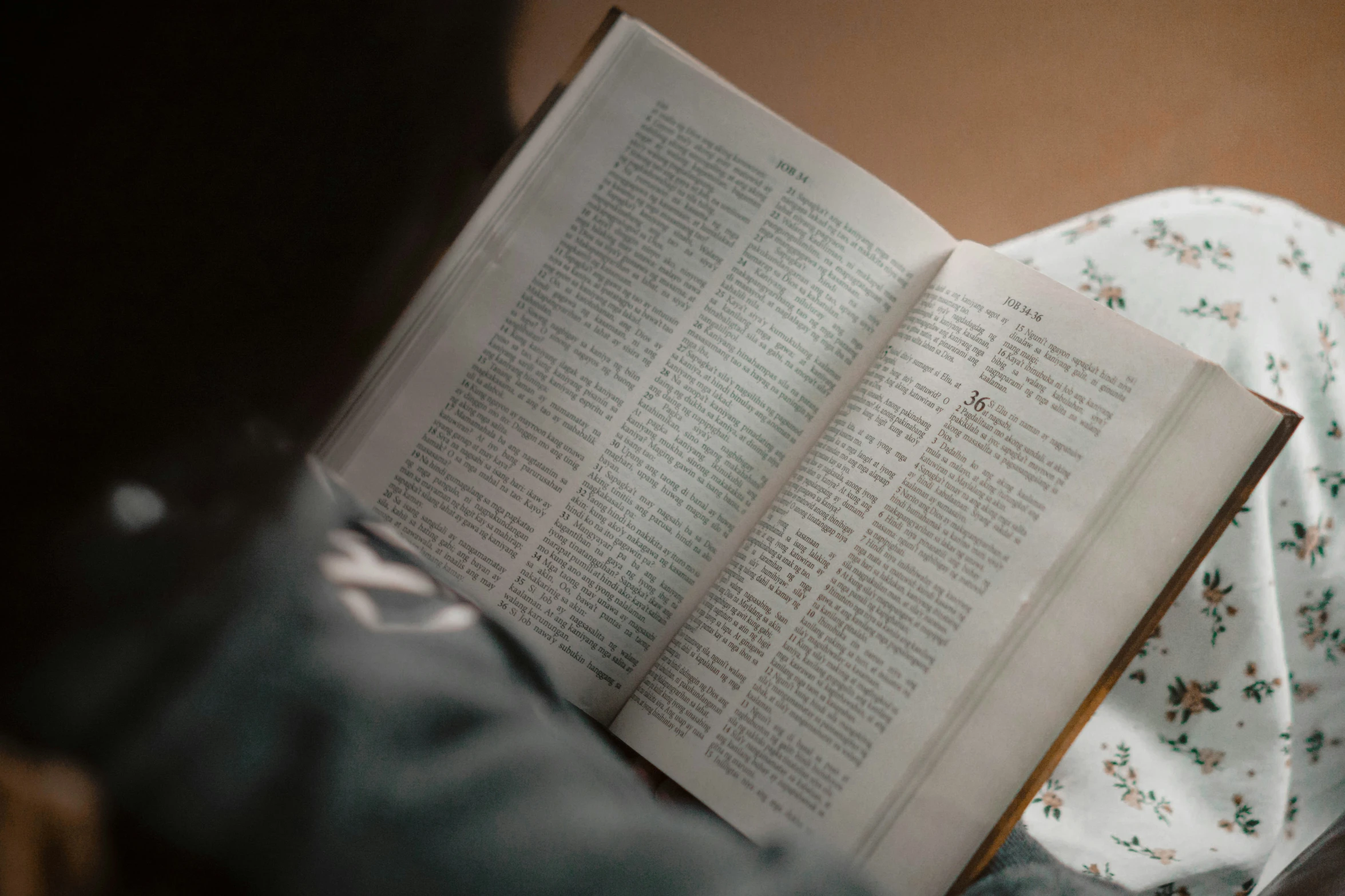 a person reading a book in bed with a white comforter