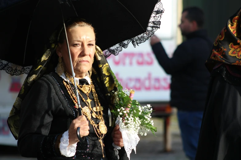 a woman in costume carrying an umbrella walks down a street