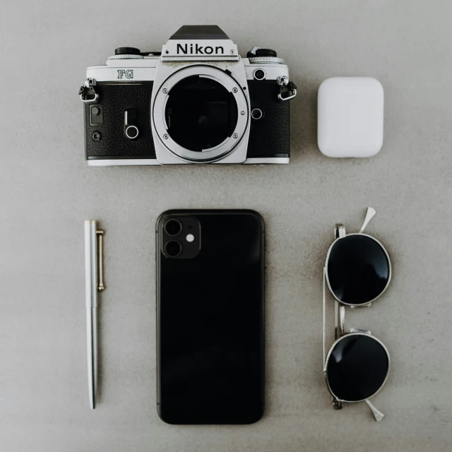 a camera, sunglasses and a phone on a table