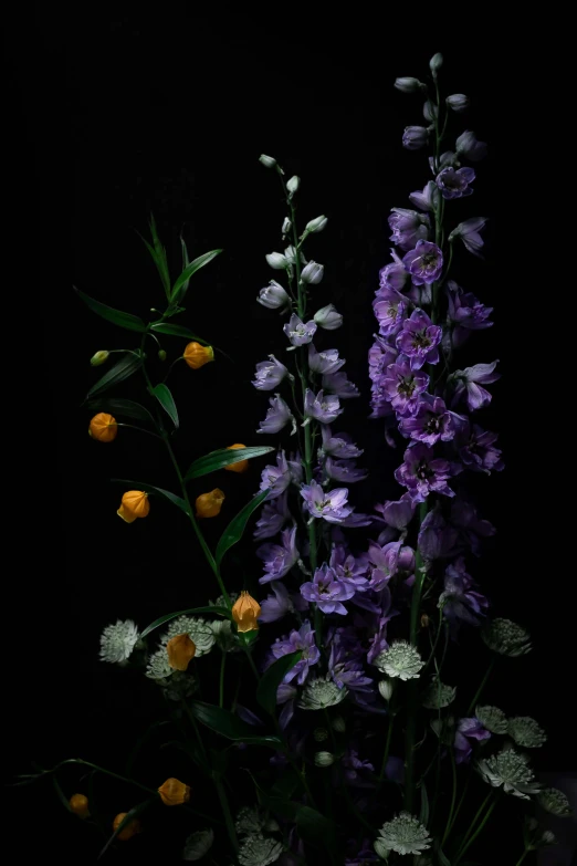 a black vase holding purple flowers and greenery