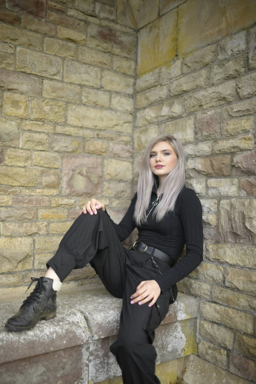 a woman sitting in a room near a brick wall