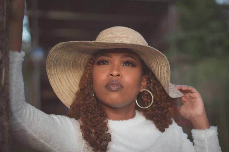 a woman with long curly hair wearing a hat and a white shirt