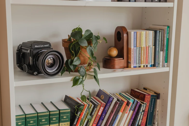 a white book shelf topped with books and a camera