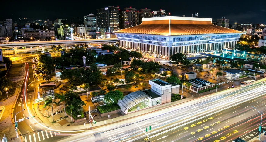 a city with buildings, street and light trails at night