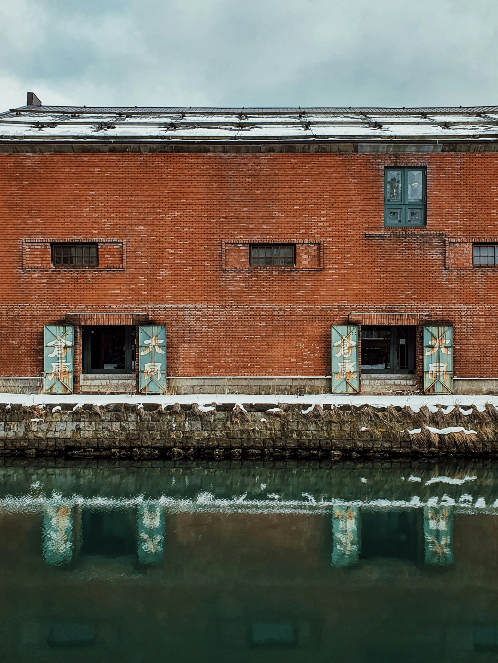 a red brick building with a window next to the water