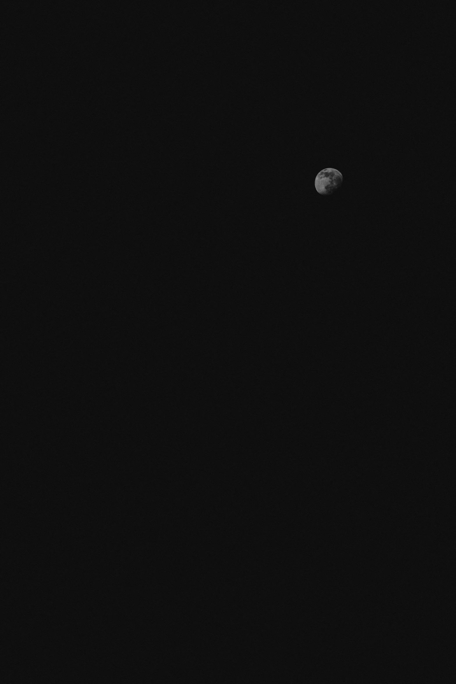 black and white pograph of the moon taken with two telescope lens and some dark clouds