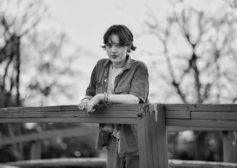 a woman standing on a wooden fence looking back at the camera