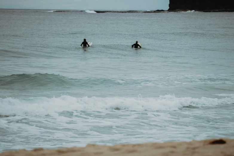 two people holding surf boards walking into the ocean