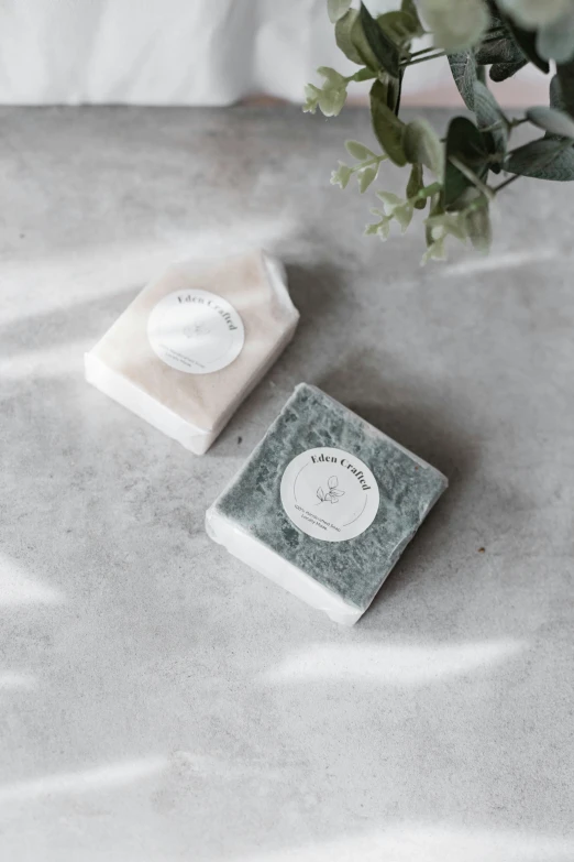 two square soap bars sit next to some flowers