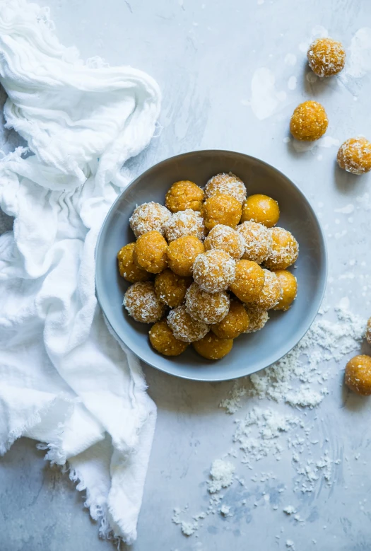 a bowl of sugar coated doughnuts next to powdered sugar