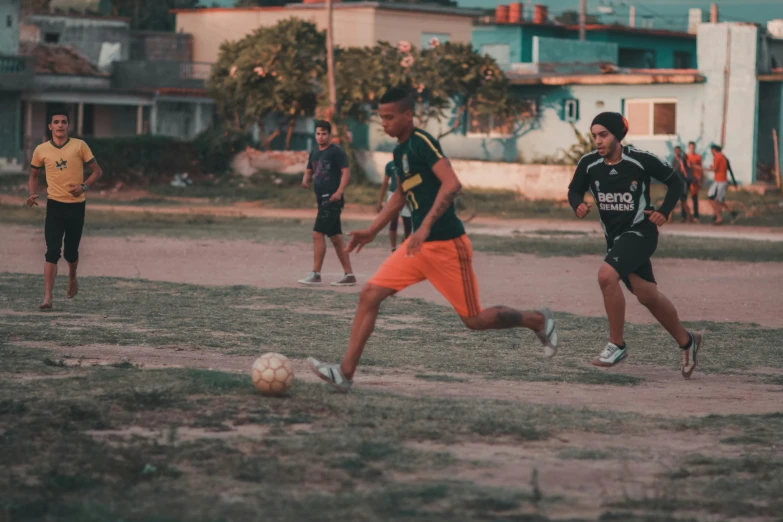 three soccer players running towards the ball on the field