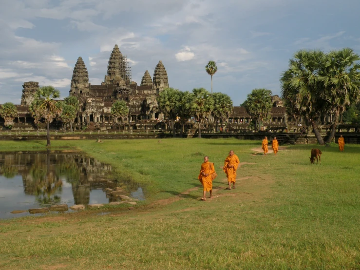 two monks in orange robes walking away from a lake