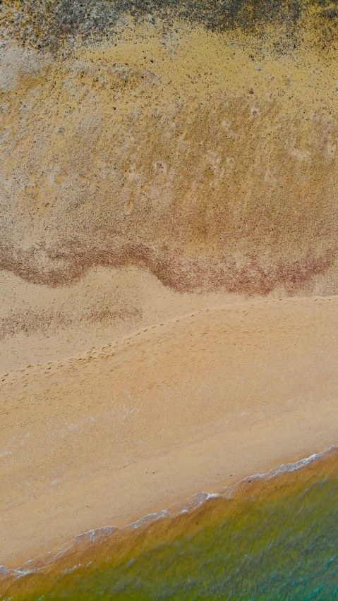 the top view of an ocean shoreline with waves crashing on the sandy shore