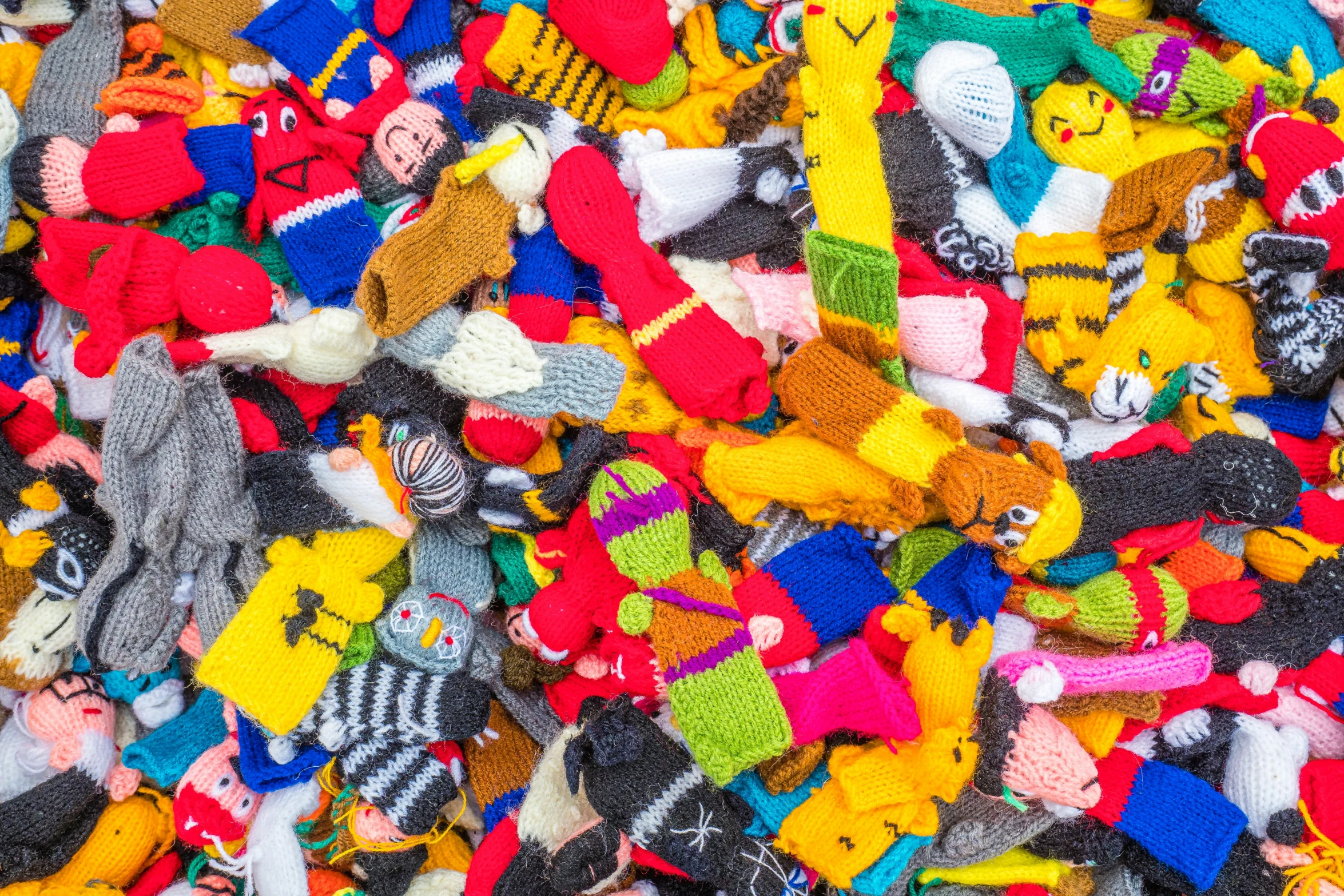 a pile of small stuffed animals made with colorful knit material