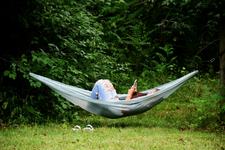 woman reads in the hammock while lying in it