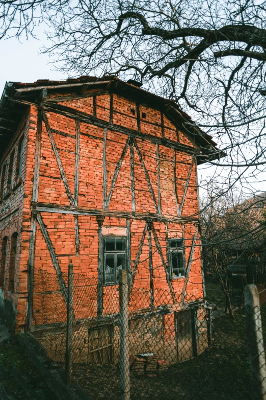 a very old red brick house with a metal fence