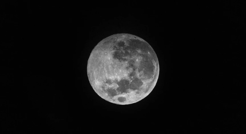 the full moon is lit and reflecting its face in black and white