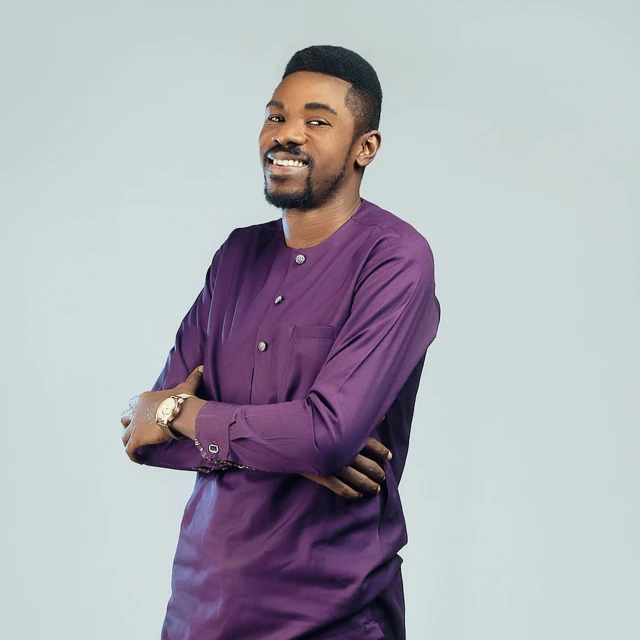 a man in a purple shirt smiling while standing