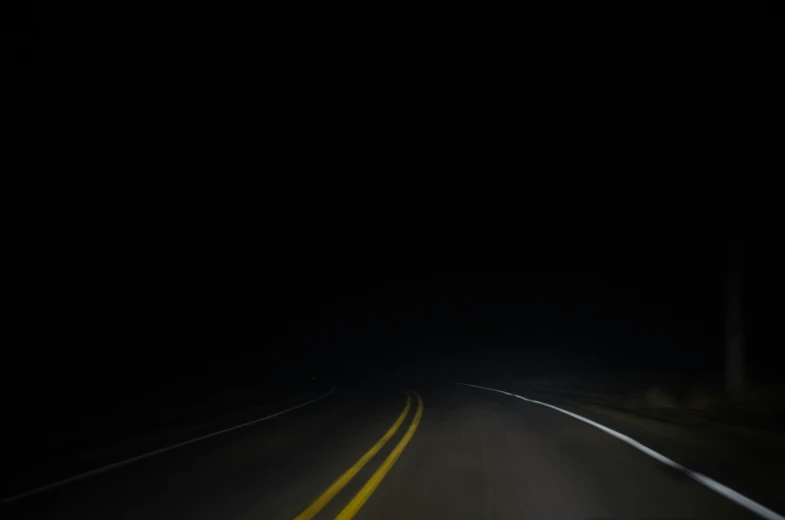 an empty road in a dark, lonely area with only lights