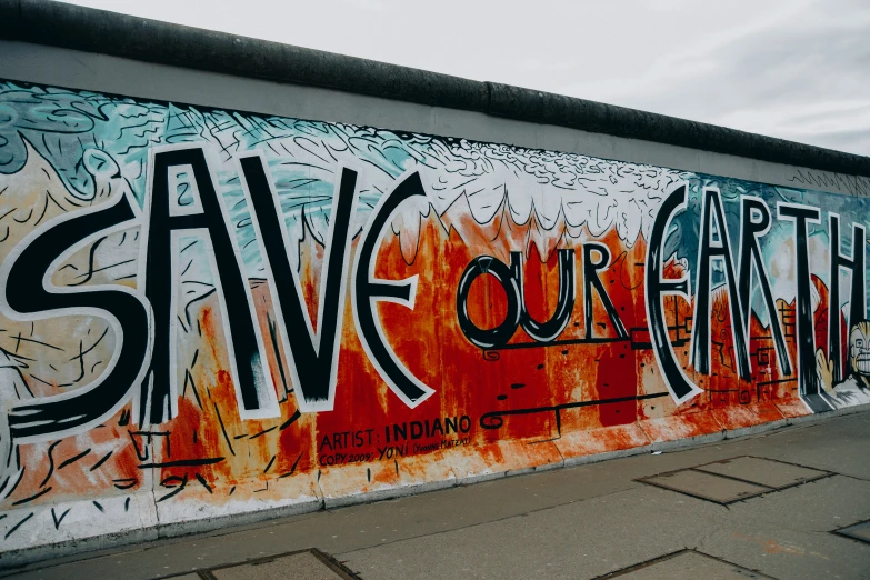 graffiti on the wall behind a bench reads save our earth