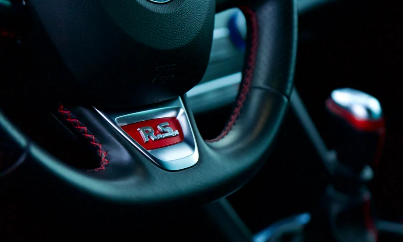 the inside view of a bmw vehicle steering wheel with a blue ke light and red stitchs on it