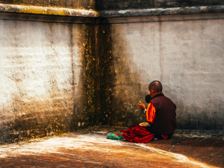 a monk sitting on the floor and talking on the phone